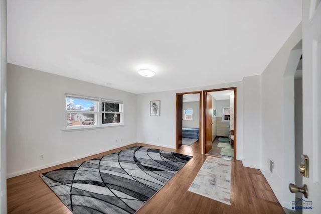 interior space featuring baseboards, arched walkways, and wood finished floors