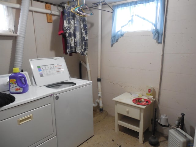 clothes washing area featuring concrete block wall, laundry area, and independent washer and dryer