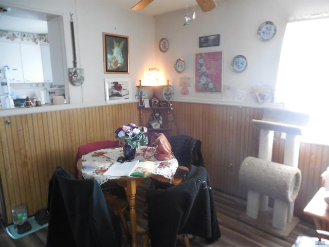 dining space with wainscoting, a ceiling fan, and wooden walls