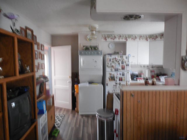 kitchen featuring stacked washer and clothes dryer, visible vents, a ceiling fan, white cabinetry, and wood finished floors