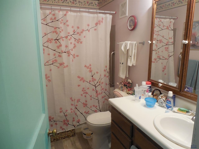 bathroom featuring visible vents, a shower with shower curtain, toilet, wood finished floors, and vanity