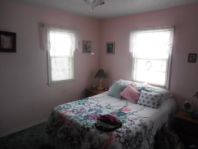 carpeted bedroom with baseboards and a textured ceiling