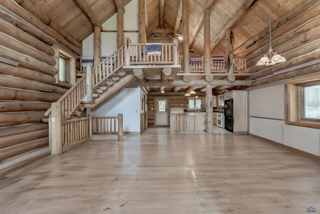 unfurnished living room featuring wood ceiling, log walls, beam ceiling, light wood-style flooring, and high vaulted ceiling