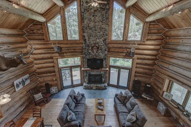 unfurnished living room featuring high vaulted ceiling, beam ceiling, a stone fireplace, hardwood / wood-style flooring, and wood ceiling