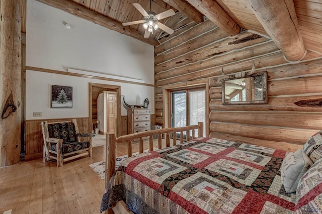 bedroom featuring light wood finished floors, wainscoting, vaulted ceiling with beams, and wood ceiling