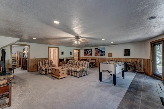 recreation room with a wainscoted wall, wood walls, and a textured ceiling