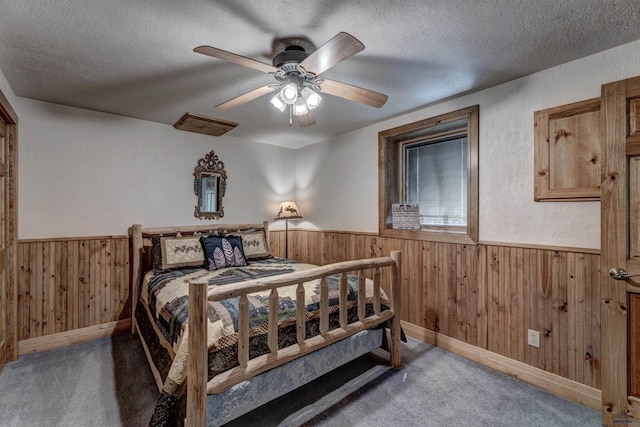 bedroom with carpet floors, wood walls, and wainscoting