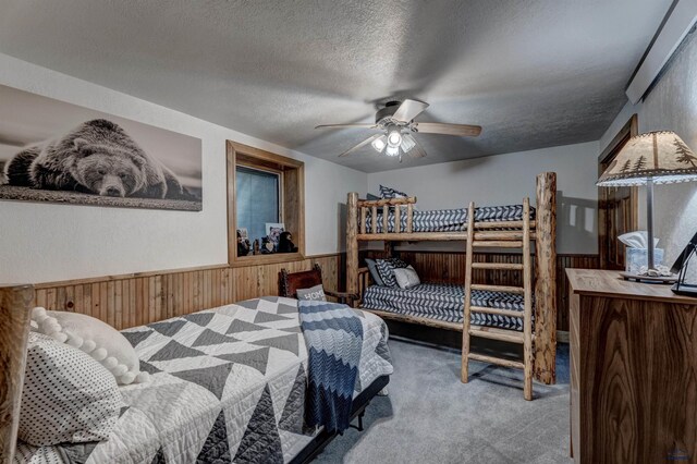 carpeted bedroom with wooden walls, a textured ceiling, and wainscoting