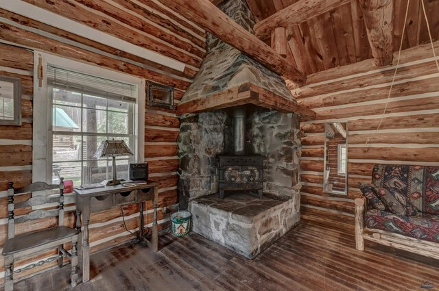 living area with rustic walls, wood finished floors, a wood stove, and vaulted ceiling