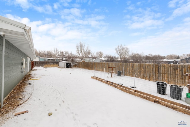 yard covered in snow featuring an outbuilding, central air condition unit, a fenced backyard, and a shed