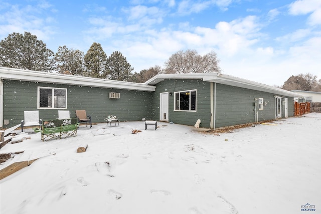 snow covered back of property with a wall mounted AC