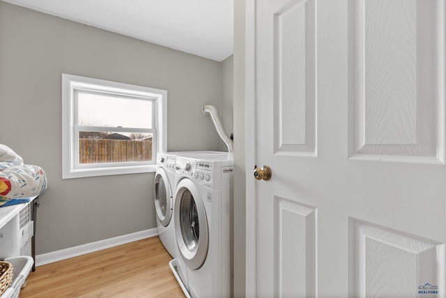 clothes washing area featuring laundry area, washing machine and dryer, baseboards, and light wood-style floors