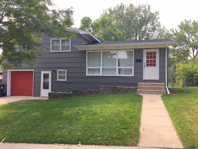 tri-level home with a garage, a front yard, and fence