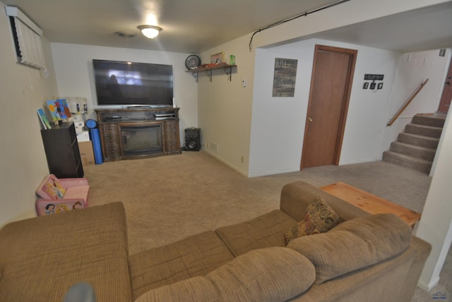 carpeted living room with a glass covered fireplace and stairs