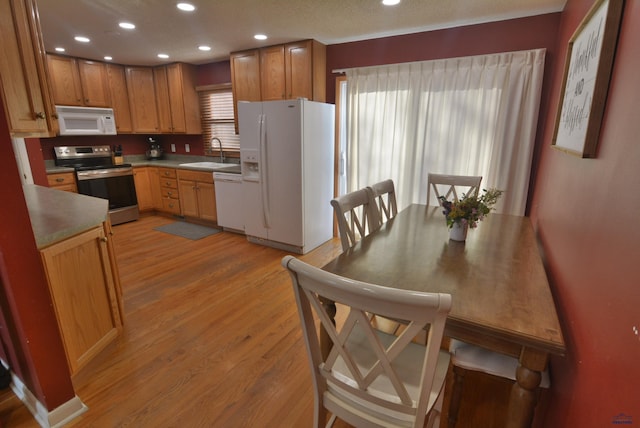 kitchen with a sink, white appliances, recessed lighting, and light wood finished floors