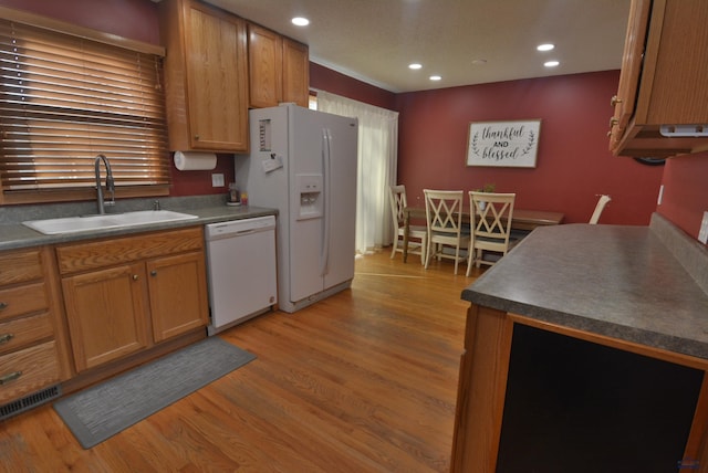 kitchen featuring white appliances, light wood-style flooring, recessed lighting, a sink, and dark countertops