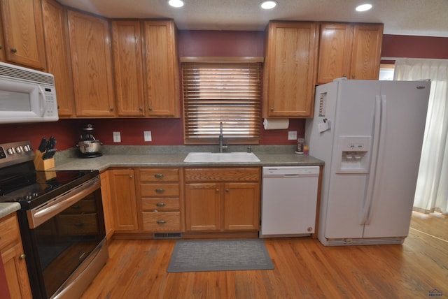 kitchen with white appliances, recessed lighting, light wood-type flooring, and a sink