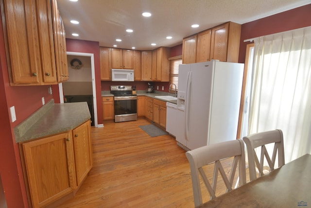 kitchen with recessed lighting, white appliances, light wood-type flooring, and a sink