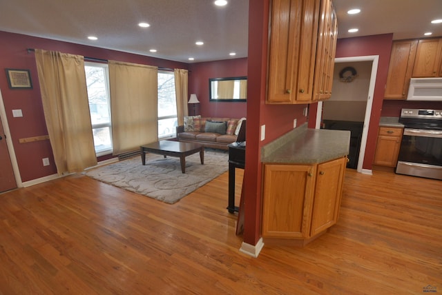 kitchen with light wood-style flooring, recessed lighting, white microwave, and stainless steel range with electric cooktop