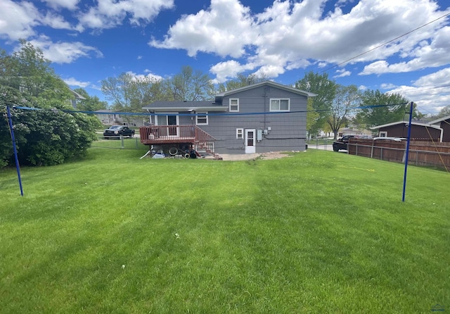 back of property with a yard, a wooden deck, and fence