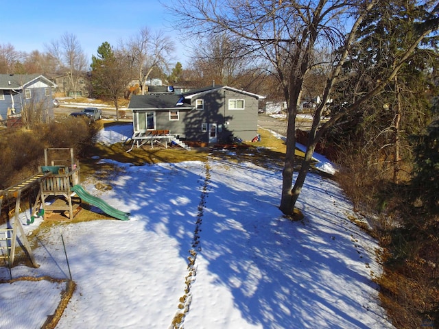 yard layered in snow featuring a playground