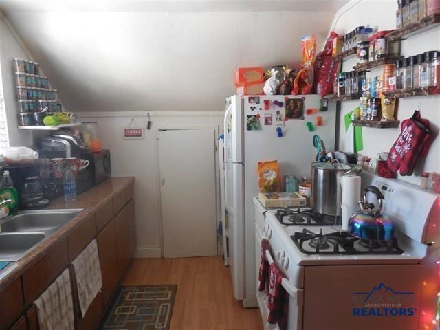 710 Haines Ave, Rapid City, SD 57701 - kitchen with a sink, lofted ceiling, light wood-style floors, and white appliances