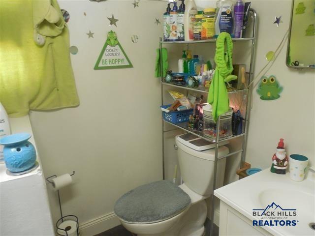 710 Haines Ave, Rapid City, SD 57701 - half bathroom featuring vanity, toilet, and baseboards