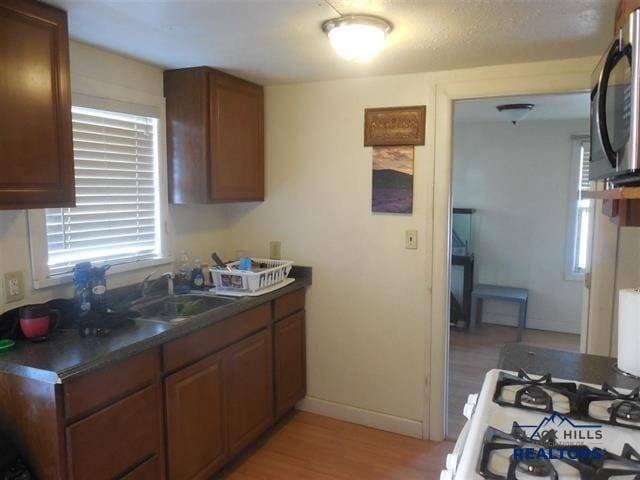 710 Haines Ave, Rapid City, SD 57701 - kitchen with dark countertops, stainless steel microwave, baseboards, light wood-style floors, and a sink