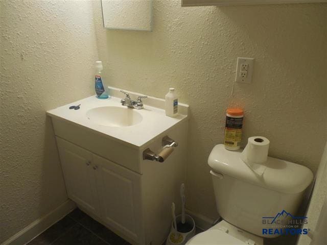 710 Haines Ave, Rapid City, SD 57701 - bathroom with toilet, tile patterned flooring, baseboards, vanity, and a textured wall