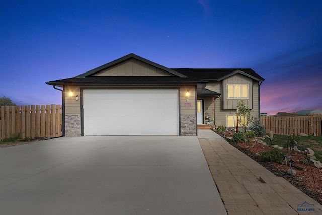 view of front facade with a garage, driveway, board and batten siding, and fence