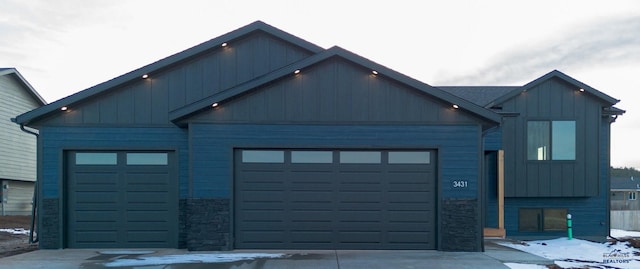 view of front of house featuring a garage, stone siding, and board and batten siding