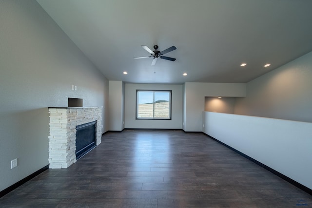 unfurnished living room with a stone fireplace, a ceiling fan, dark wood-type flooring, and baseboards