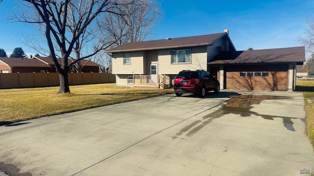 exterior space featuring a lawn, an attached garage, driveway, and fence