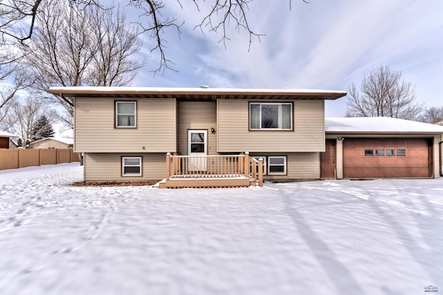 bi-level home with a deck, a garage, and fence