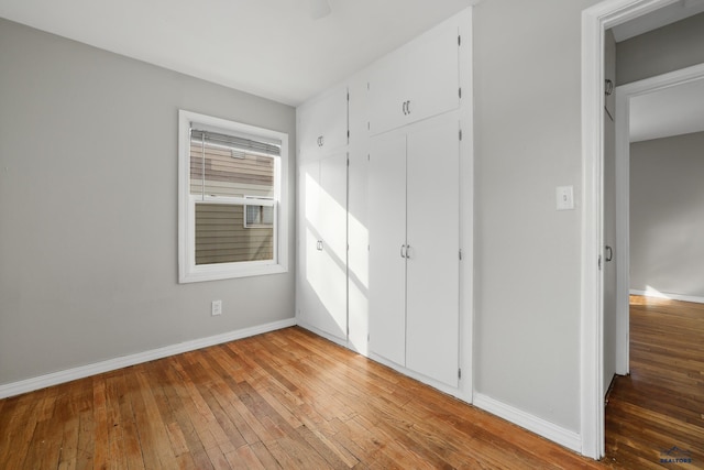 unfurnished bedroom featuring a closet, baseboards, and hardwood / wood-style flooring