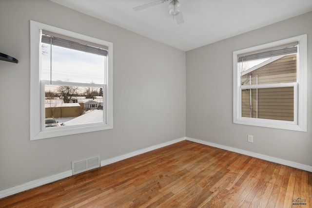 spare room featuring visible vents, a ceiling fan, baseboards, and hardwood / wood-style flooring