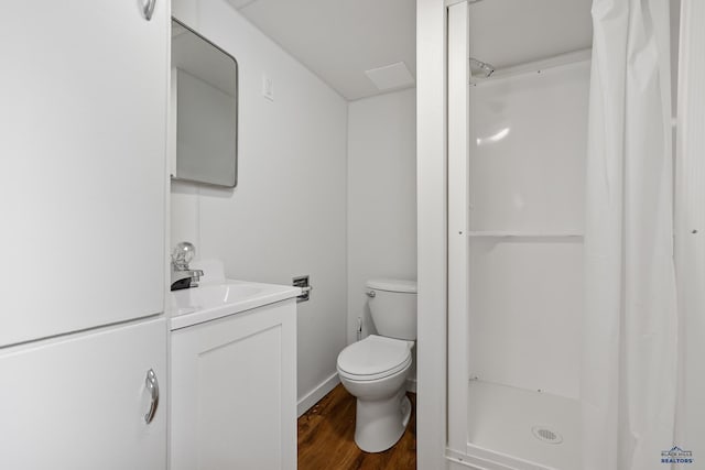 bathroom featuring vanity, a shower stall, toilet, and wood finished floors