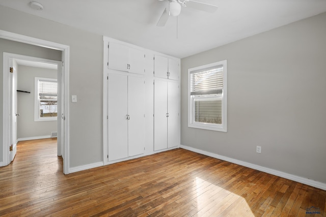 unfurnished bedroom featuring visible vents, a ceiling fan, a closet, wood-type flooring, and baseboards