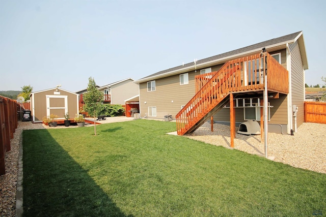 rear view of house featuring stairway, a wooden deck, a storage shed, a fenced backyard, and an outdoor structure