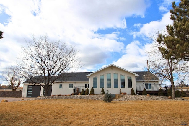 back of house featuring stucco siding, a lawn, and a garage