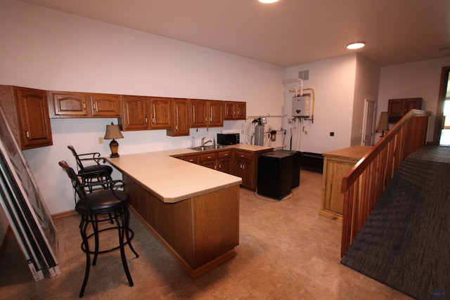 kitchen with a peninsula, water heater, a sink, black microwave, and a kitchen breakfast bar