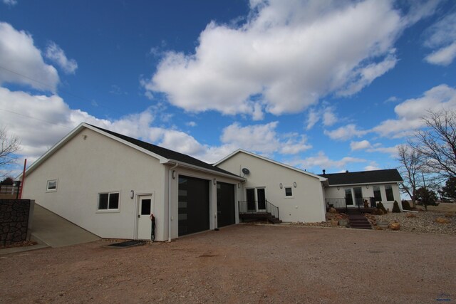 back of house with stucco siding, driveway, and a garage