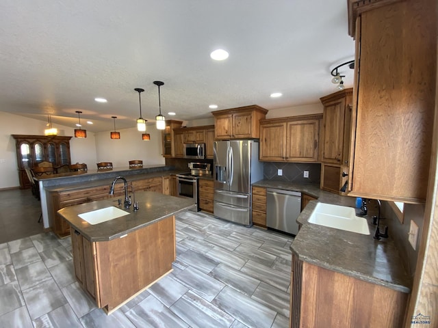 kitchen featuring a peninsula, a sink, decorative backsplash, stainless steel appliances, and brown cabinets