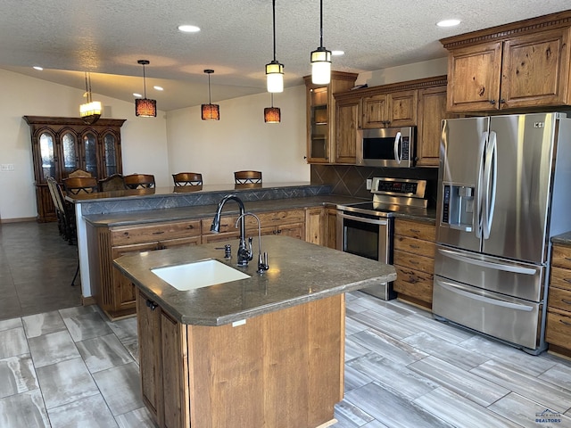 kitchen with brown cabinets, a sink, tasteful backsplash, stainless steel appliances, and a peninsula