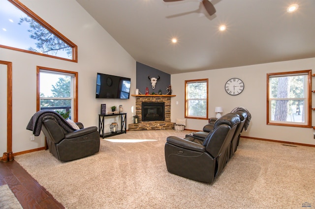 carpeted living area featuring a fireplace, high vaulted ceiling, baseboards, and a ceiling fan