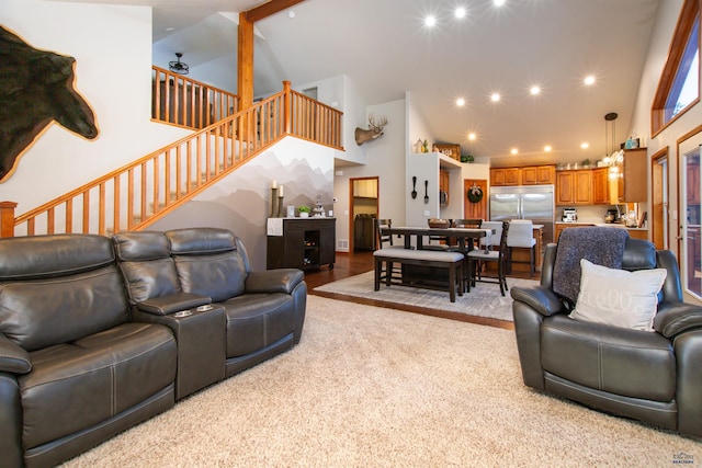 carpeted living room with stairs, recessed lighting, and high vaulted ceiling