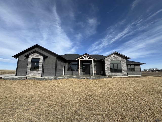 view of front of property featuring stone siding and a front yard