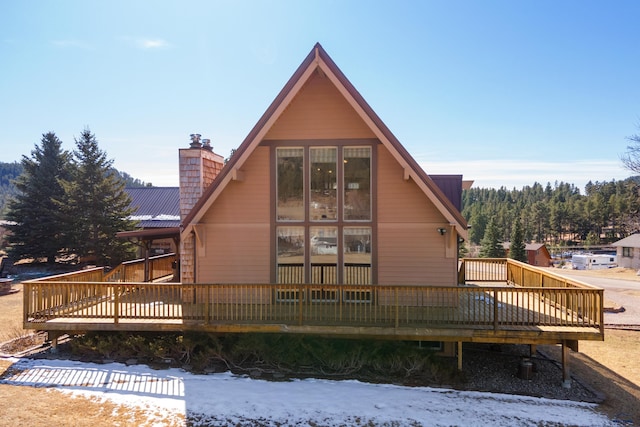 rear view of property featuring a wooden deck and a chimney