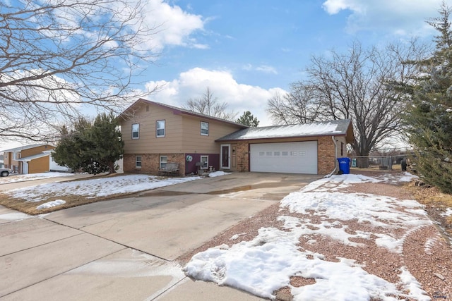 split level home featuring brick siding, an attached garage, and driveway