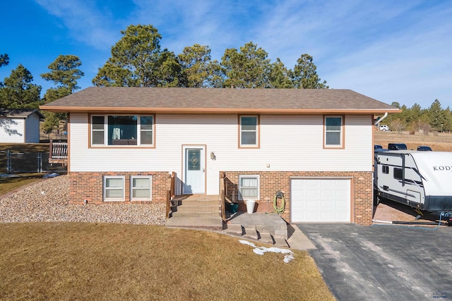 bi-level home featuring aphalt driveway, brick siding, a garage, and a front yard